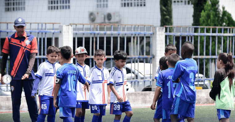 Entrenador dando indicaciones a los niños en la cancha